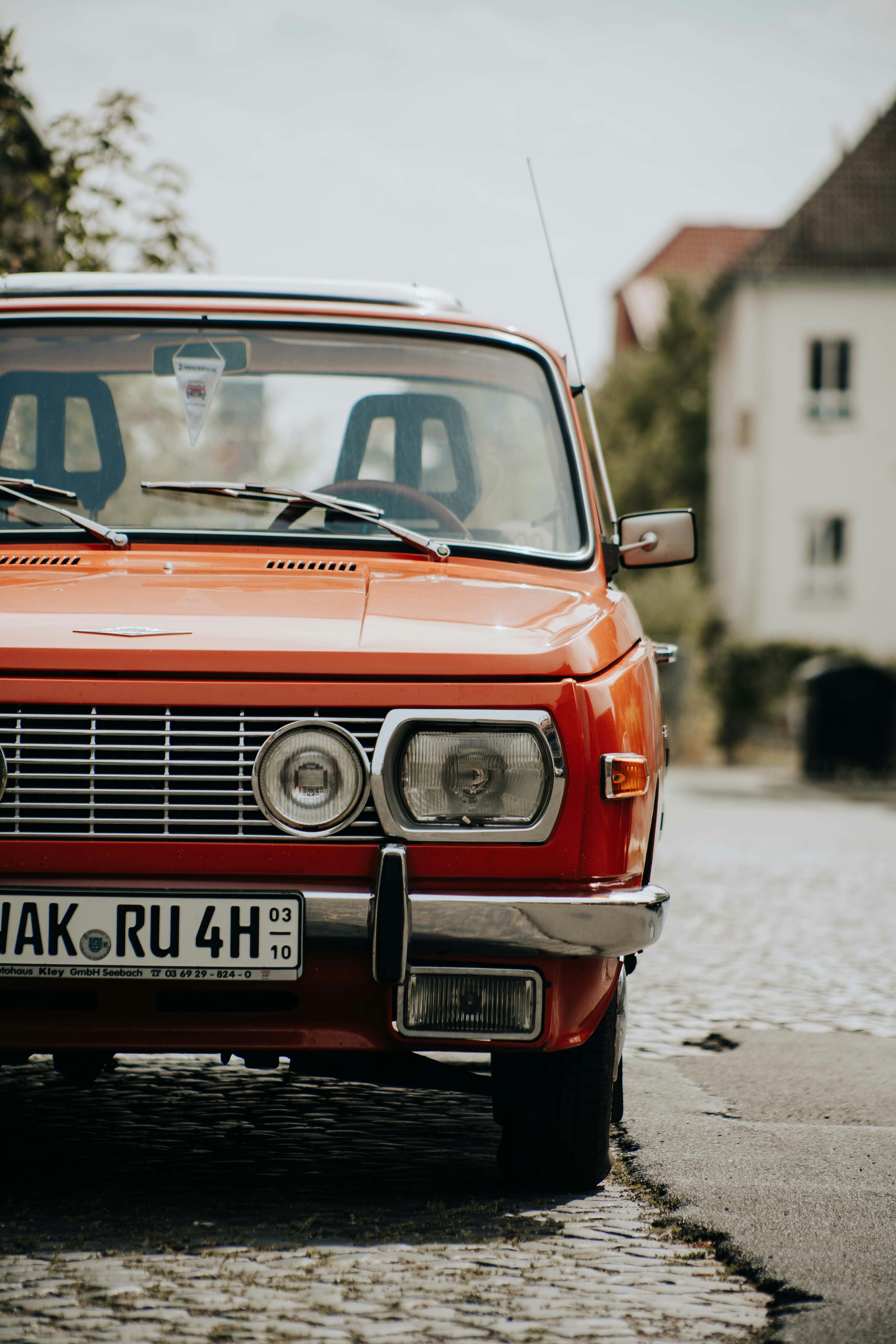 an orange car parked on a cobblestone street