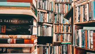 A densely packed library filled with books on wooden shelves. The image prominently features stacks of books in the foreground with various titles, while more shelves filled with books recede into the background. The scene is rich with literature and conveys an atmosphere of knowledge.