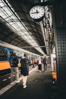 a group of people standing next to a train at a train station