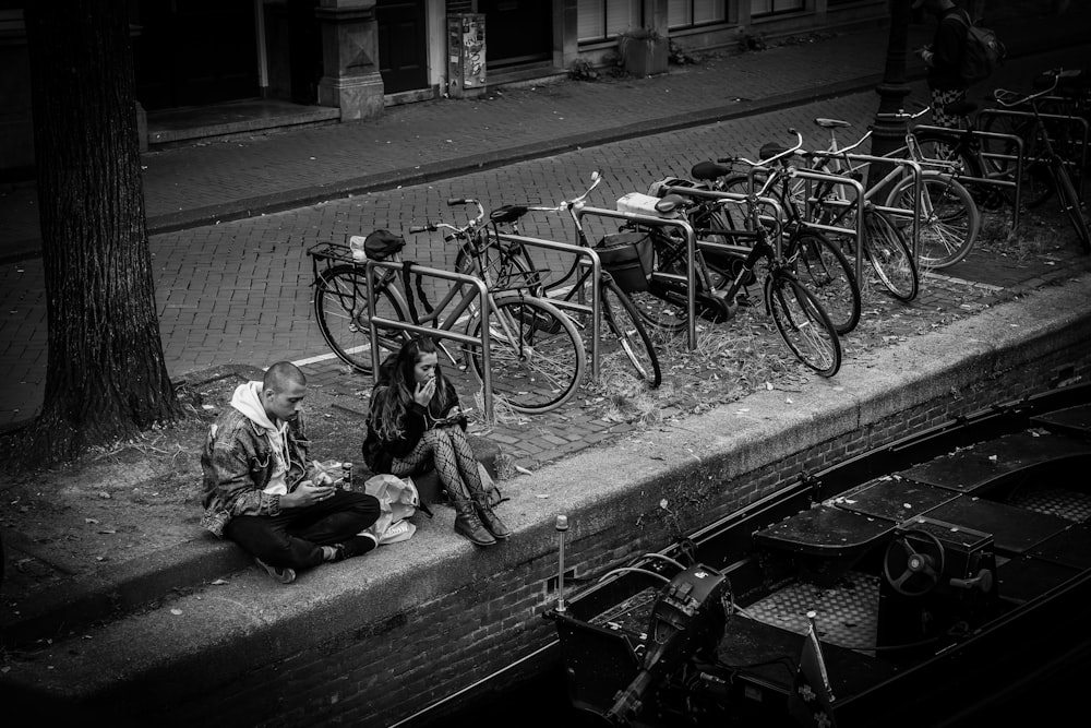 a man sitting on the side of a road next to a bunch of bikes