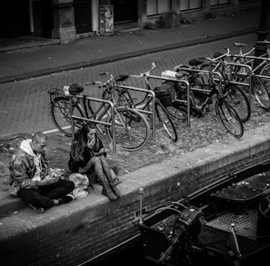 a man sitting on the side of a road next to a bunch of bikes