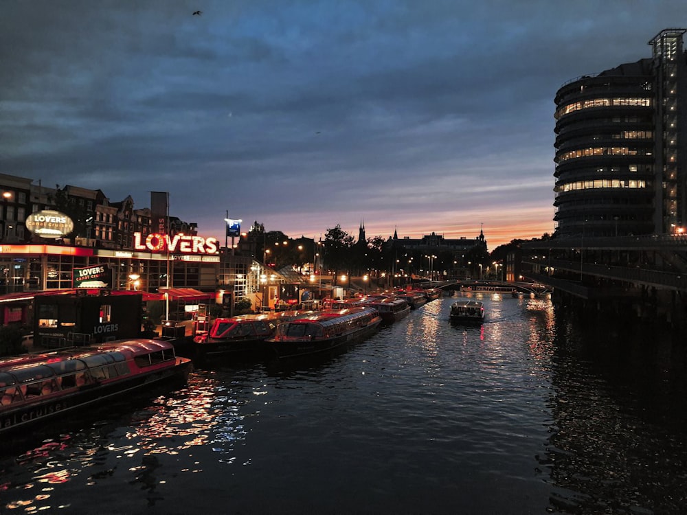 a river filled with lots of boats next to tall buildings