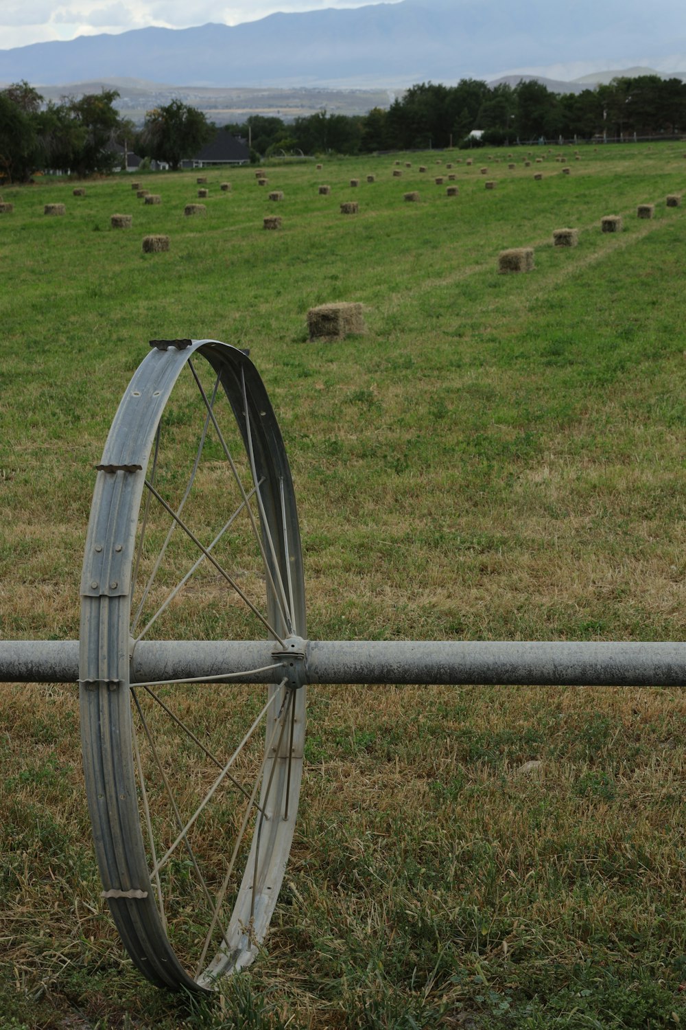 an old wheel leaning on a fence in a field