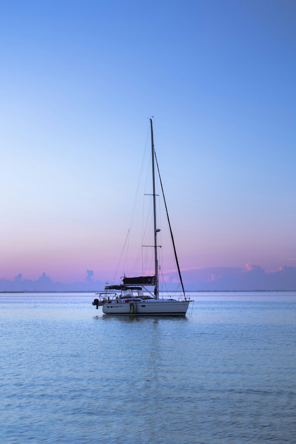 a sailboat floating in the ocean at sunset