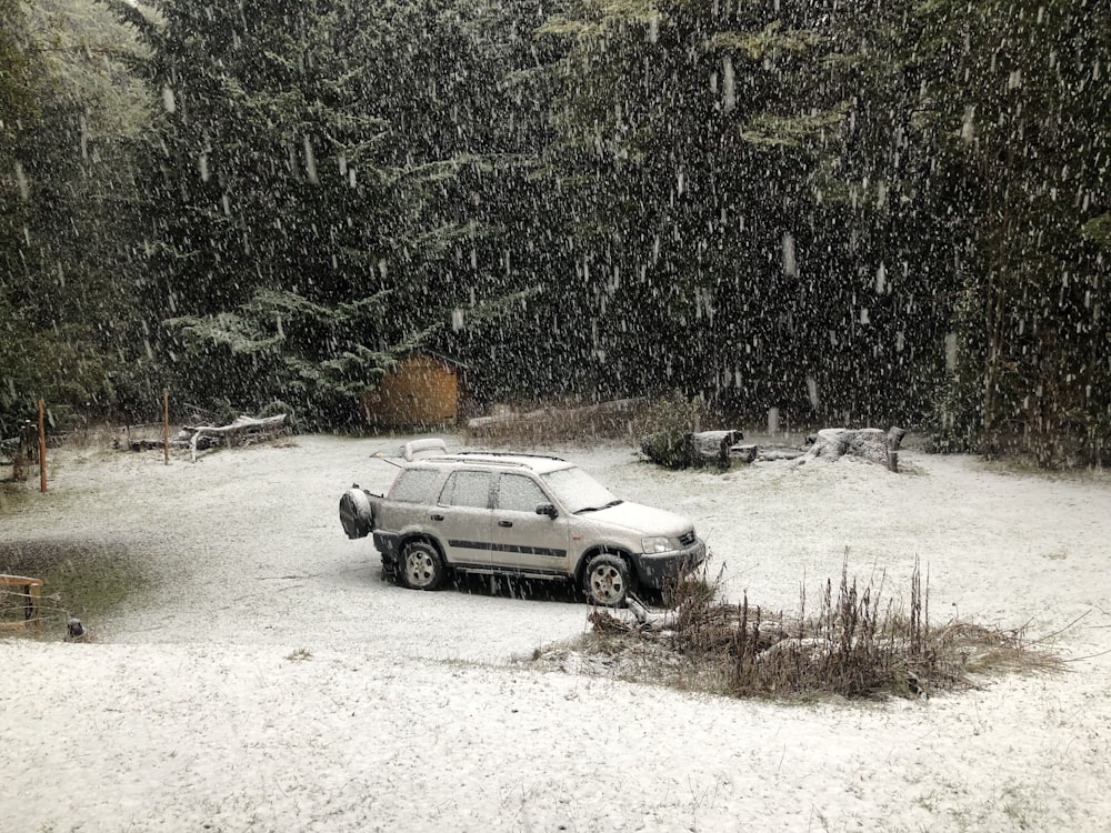 a car is parked in the snow in front of some trees