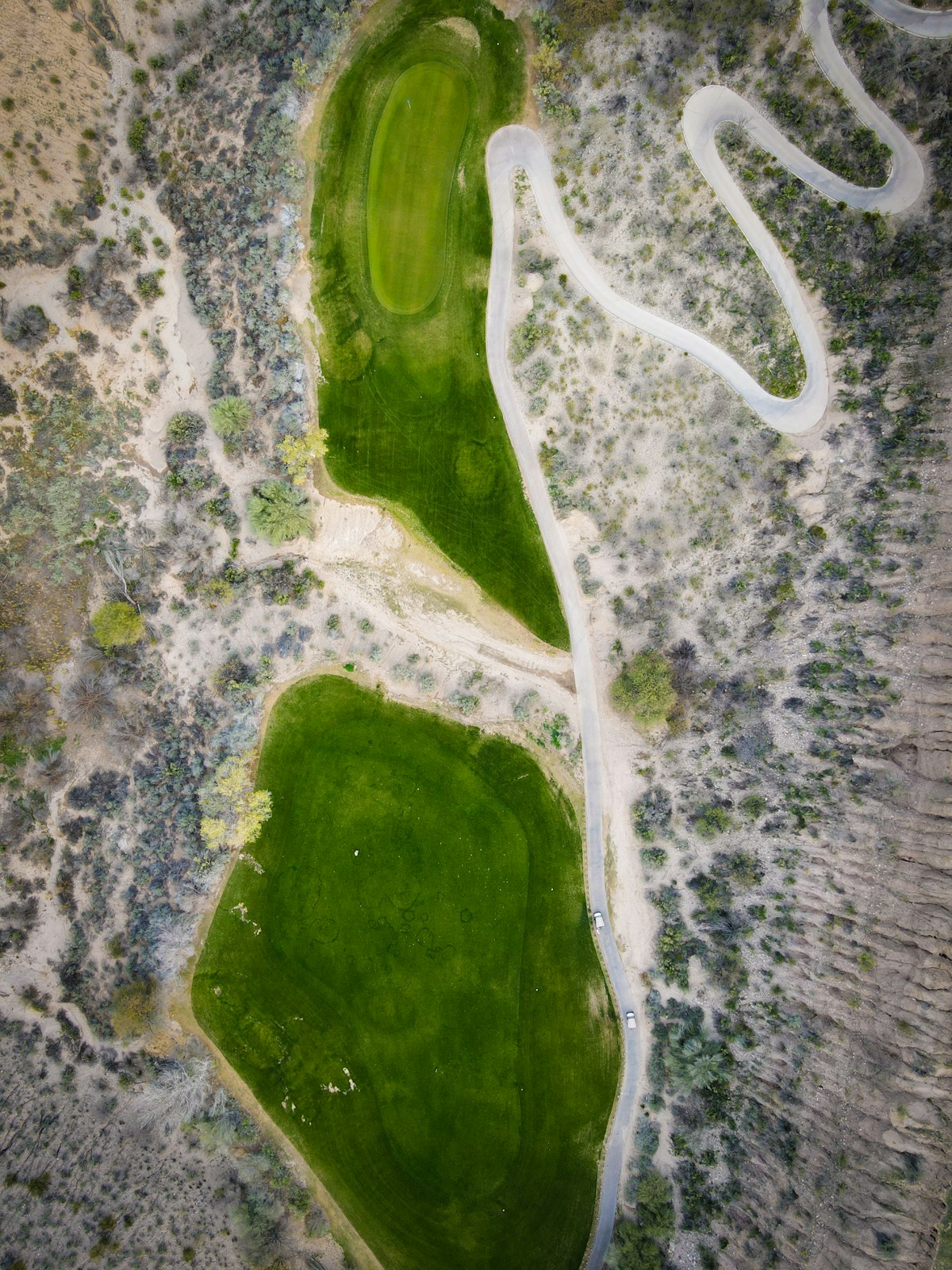Aerial view of a golf course fairway, greens, and bunkers from a drone