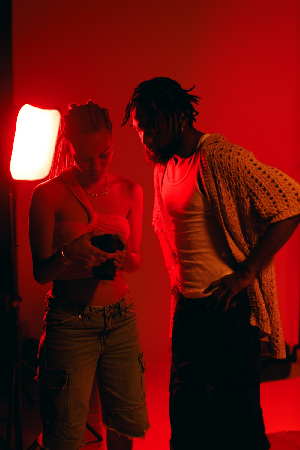 a man and a woman standing in front of a red light