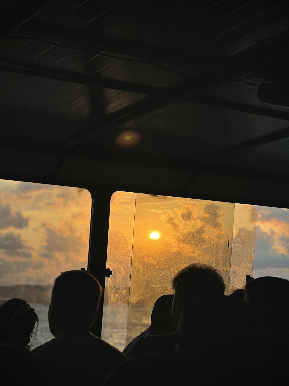 Un groupe de personnes sur un bateau regardant le soleil se coucher