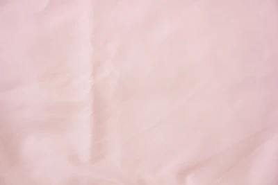 A delicate blush pink fabric swatch layered softly with warm sand and gentle taupe textiles.