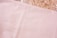 A crumpled foil sheet spreads across the top section, reflecting light with a metallic sheen. Below, a smooth, soft-textured beige or light pink fabric is visible, covering most of the image.