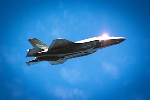 A military aircraft soaring above a clear blue sky, symbolizing readiness.