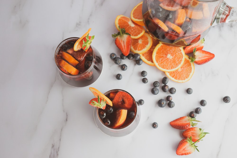two glasses of iced tea with orange slices and blueberries