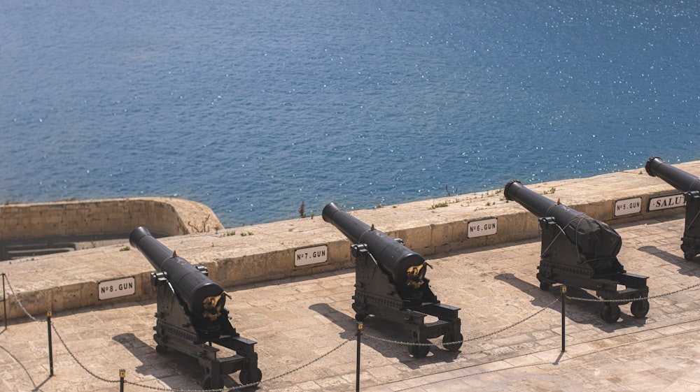 a group of black cannon sitting on top of a cement ground