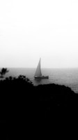 Black and white cinematic shot of a boat's prow cutting through calm sea waters at dawn.