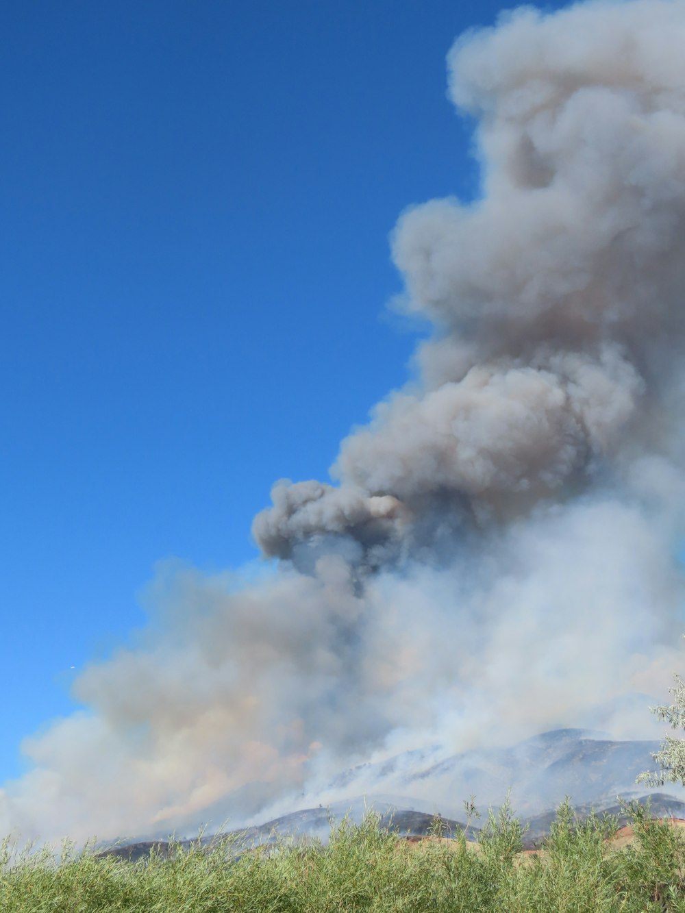 a large plume of smoke billowing from a mountain