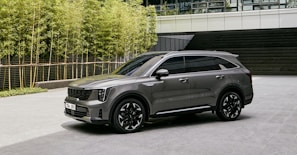 A sleek green hybrid SUV parked in front of a modern glass office building.