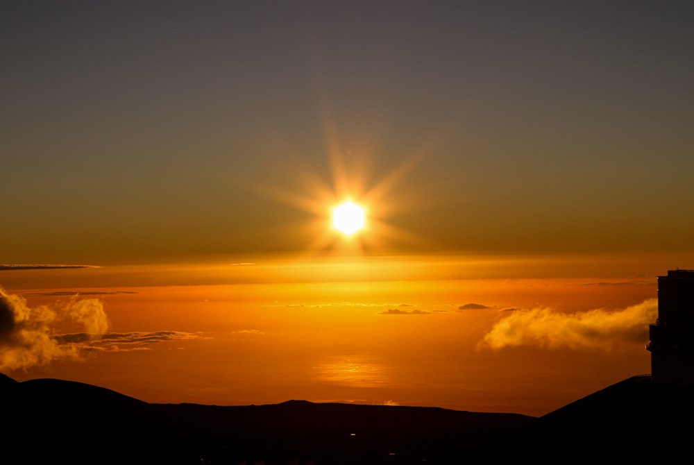 the sun is setting over the clouds in the sky