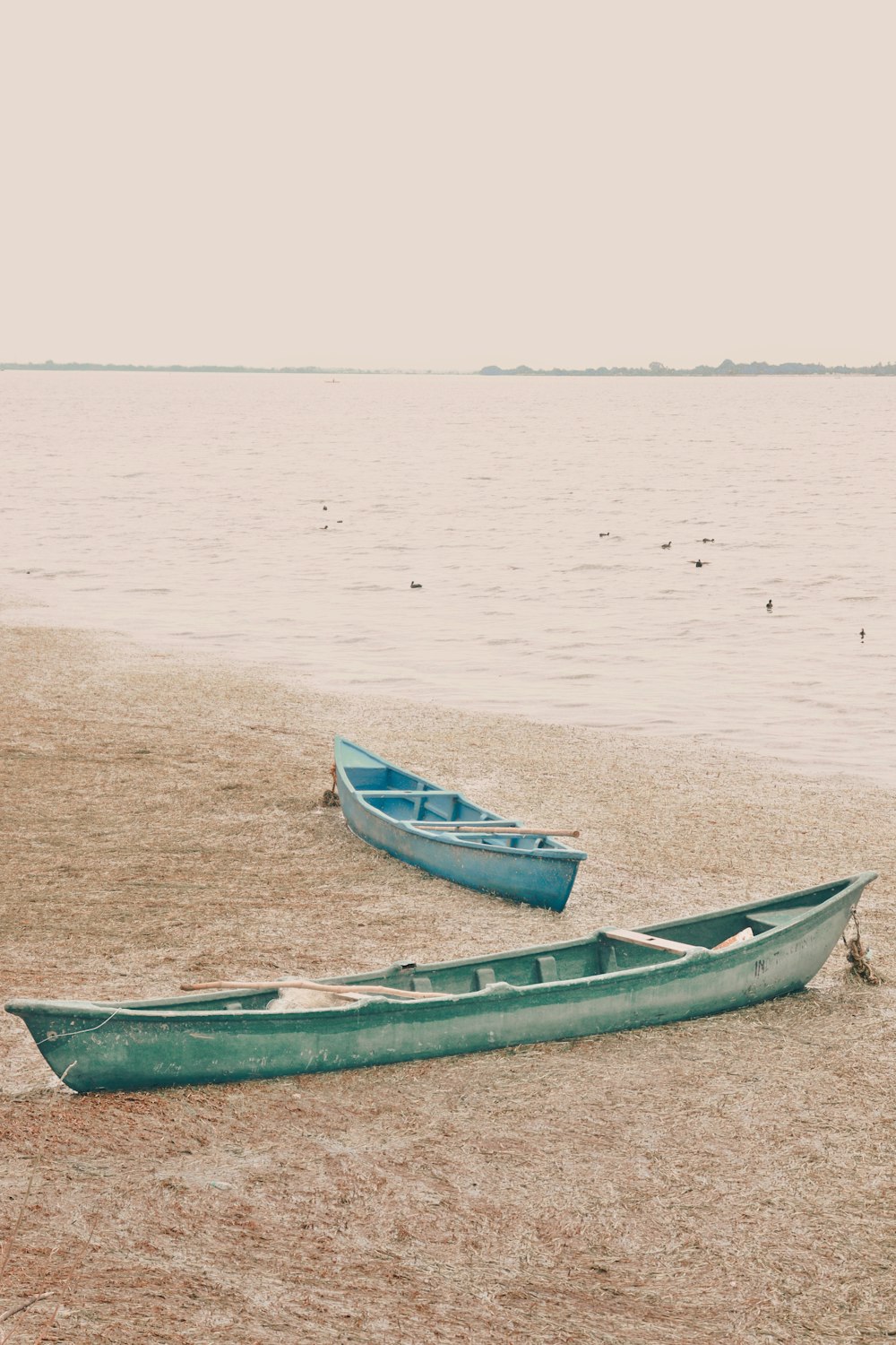 a couple of boats sitting on top of a sandy beach