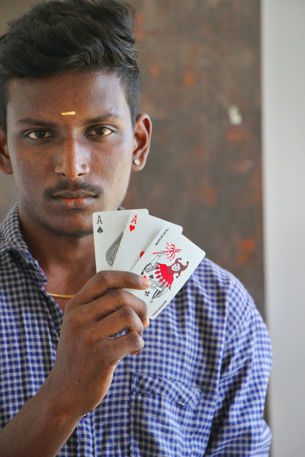 a young man holding four playing cards in his hands