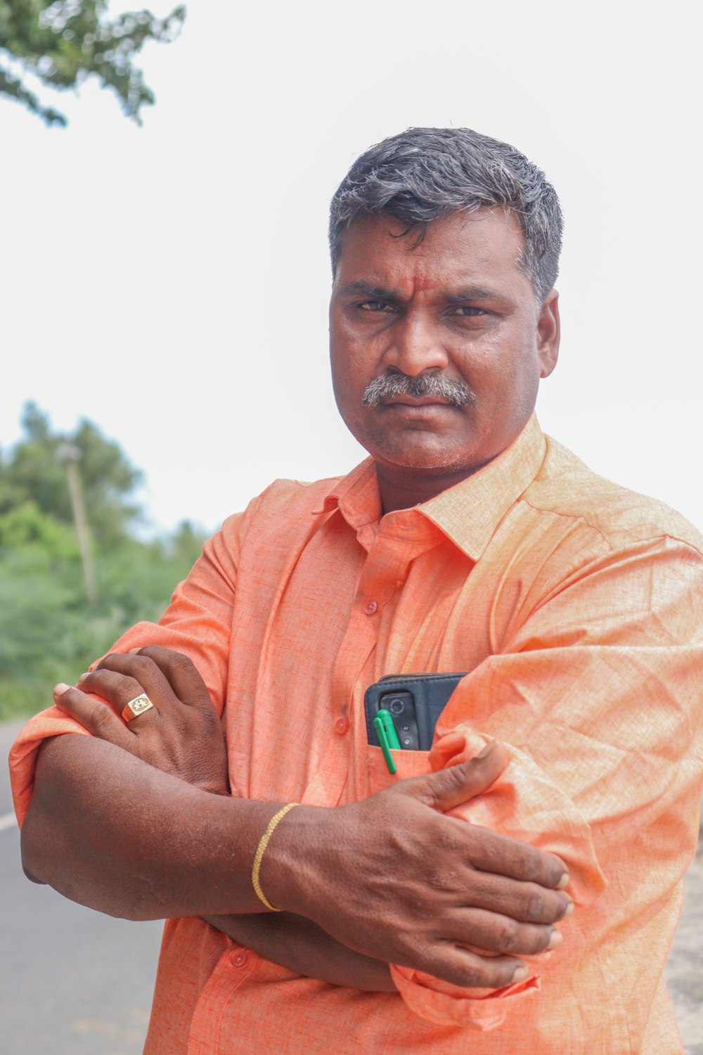 a man in an orange shirt holding a cell phone