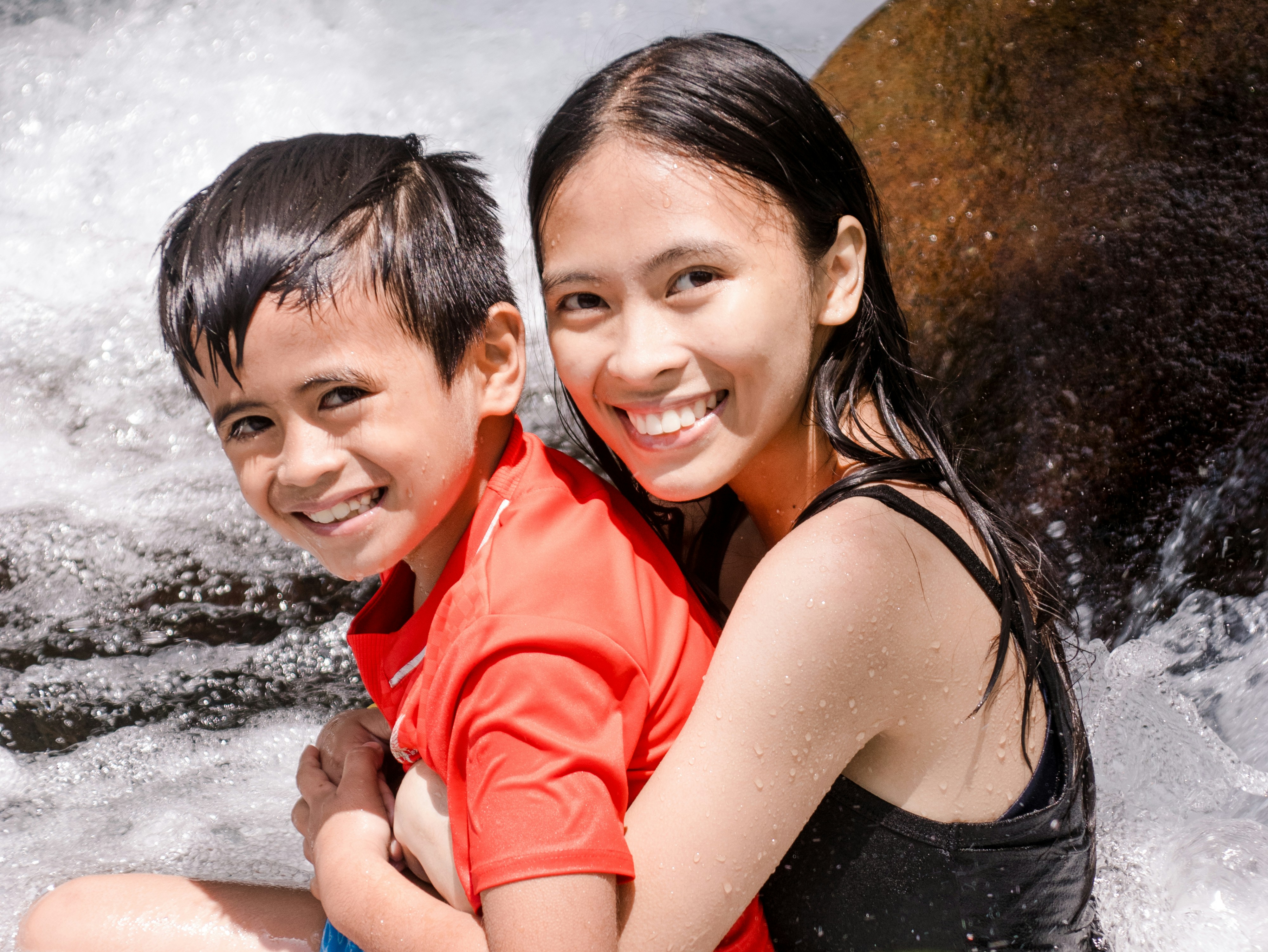 a boy and a girl are sitting in the water