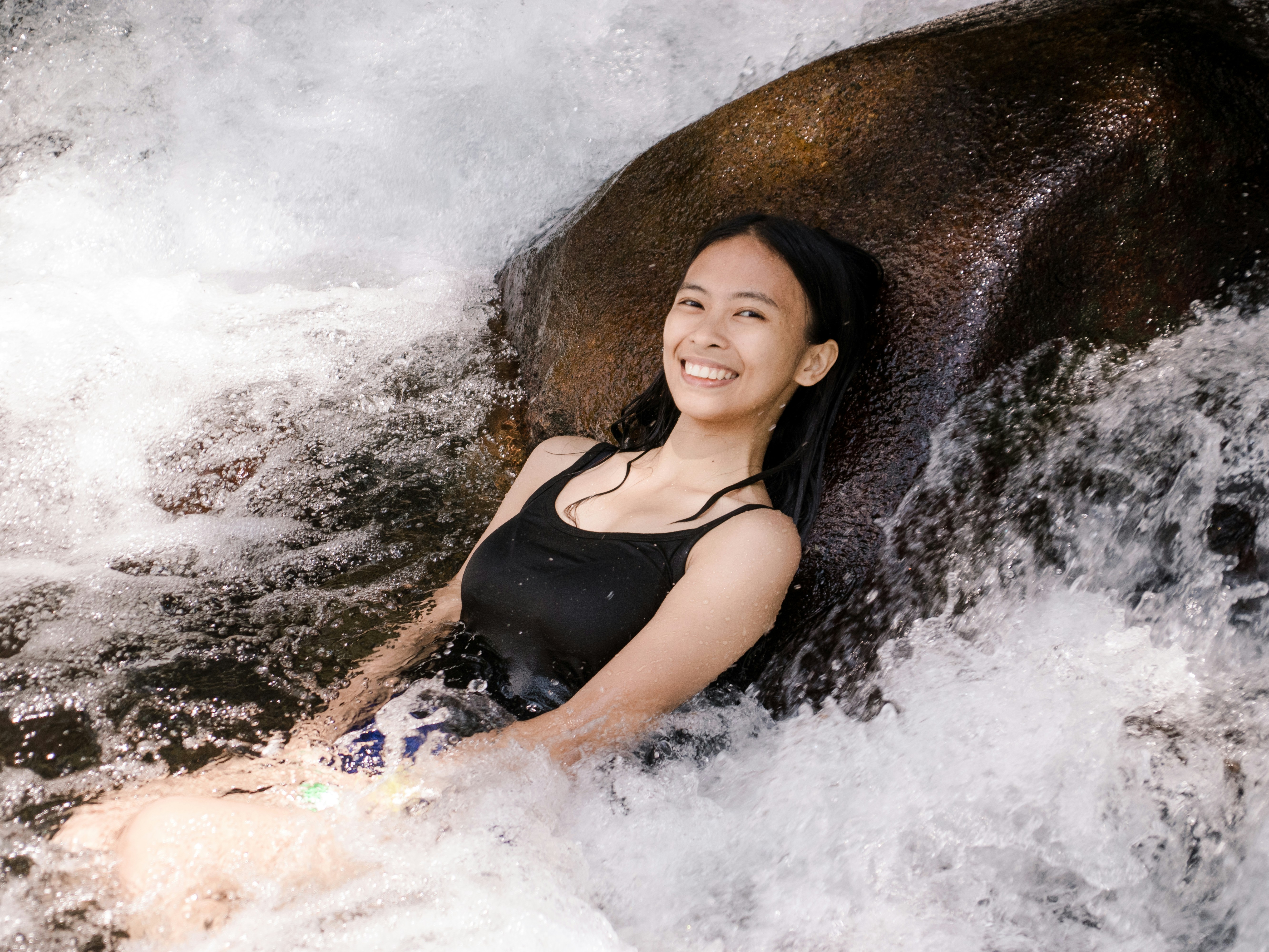 a woman laying on a rock in the water
