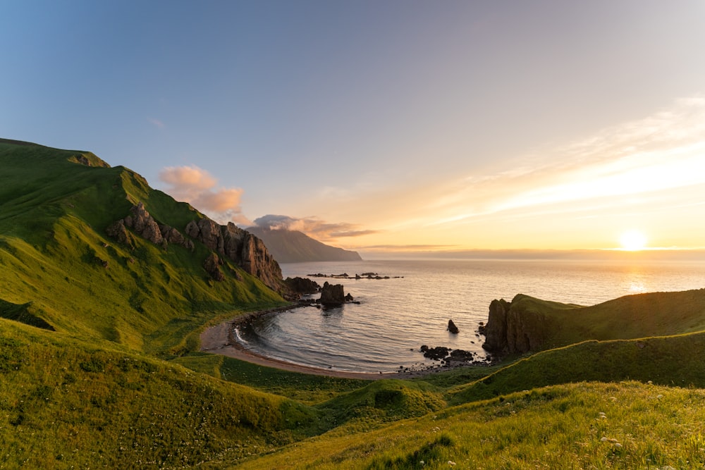 the sun is setting over the ocean and a beach