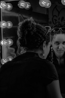 A client admiring their fresh blowout in a large mirror with warm lighting.