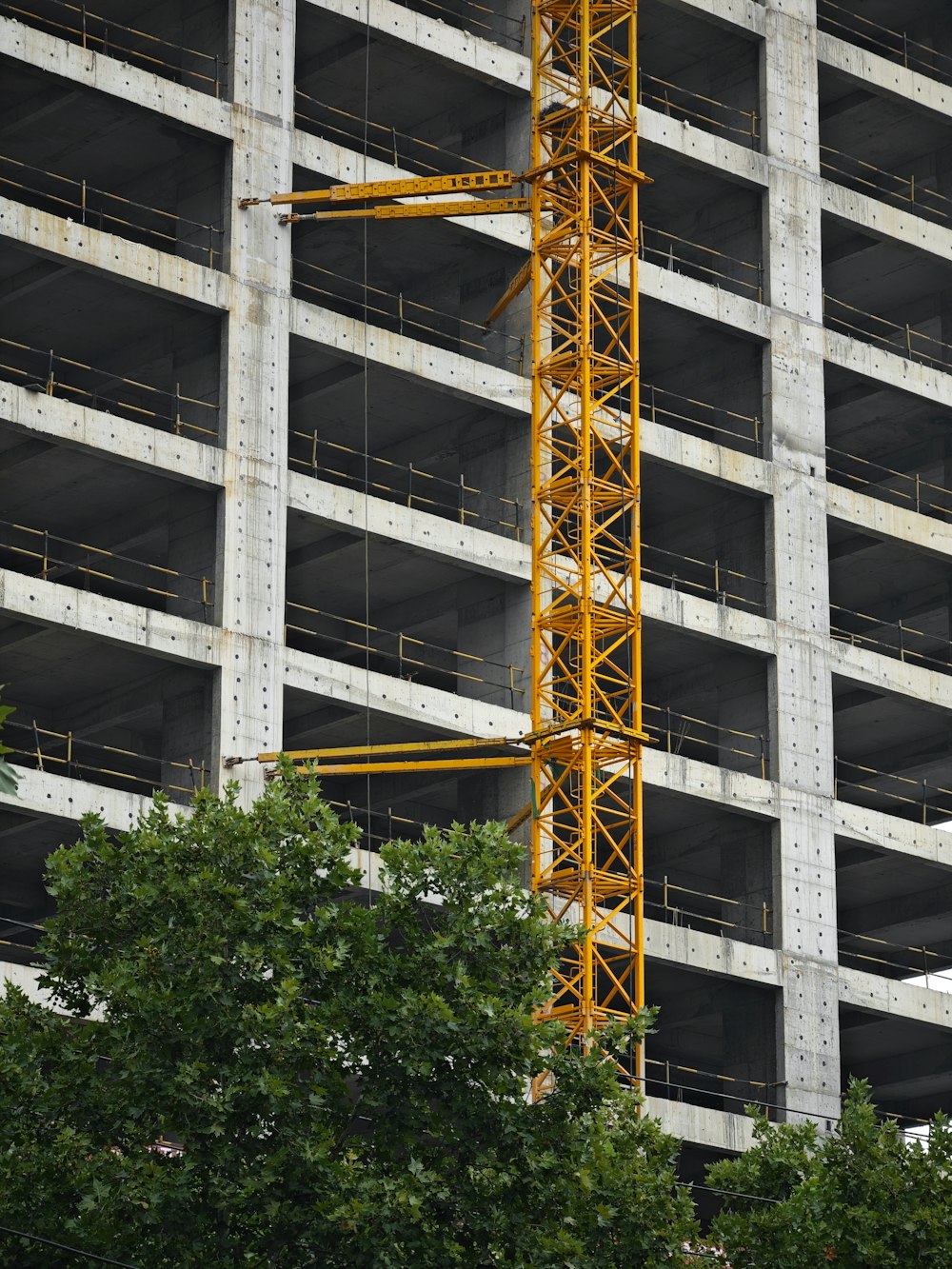 a tall yellow crane sitting in front of a tall building