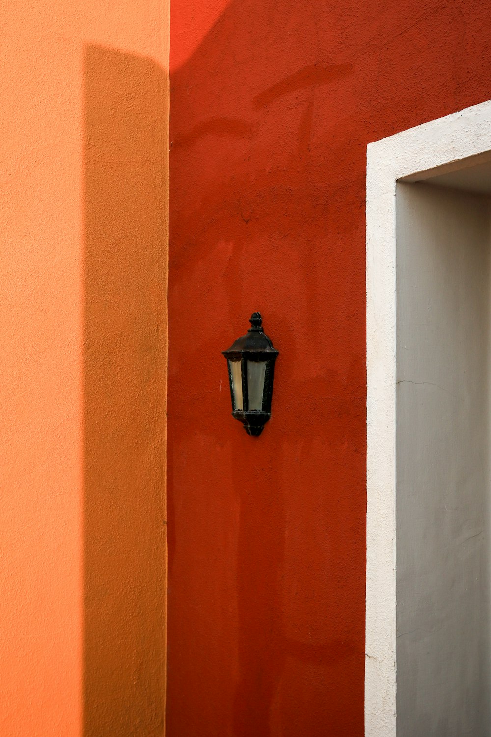 a lamp on a red wall next to a white door
