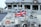 A naval ship with the Union Jack flag prominently displayed, surrounded by various equipment and lifebuoys. The vessel's structure includes windows and metallic surfaces.