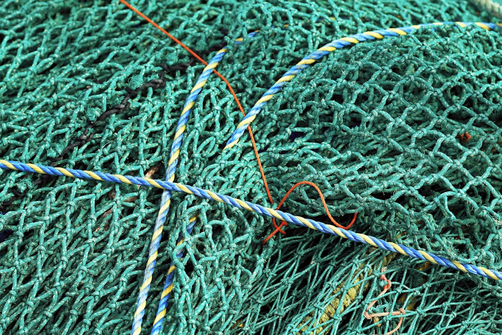 Ein Haufen grüner Fischernetze, die auf einem Strand sitzen