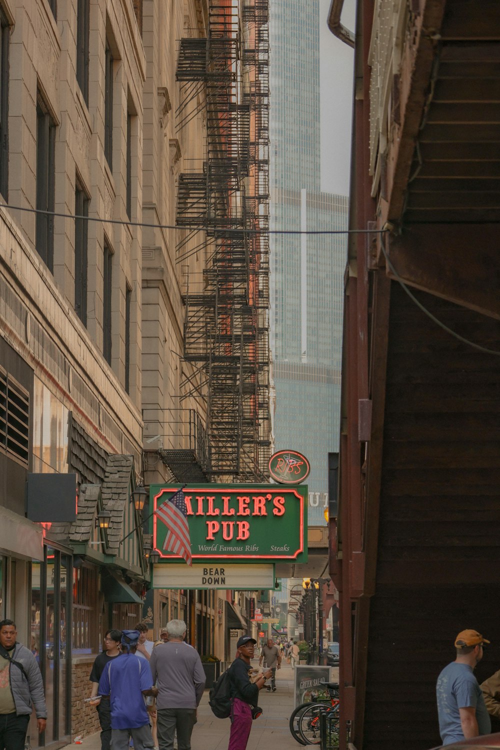 a group of people walking down a street next to tall buildings