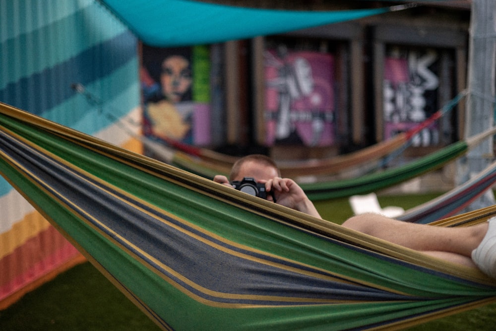 a man laying in a hammock using a cell phone