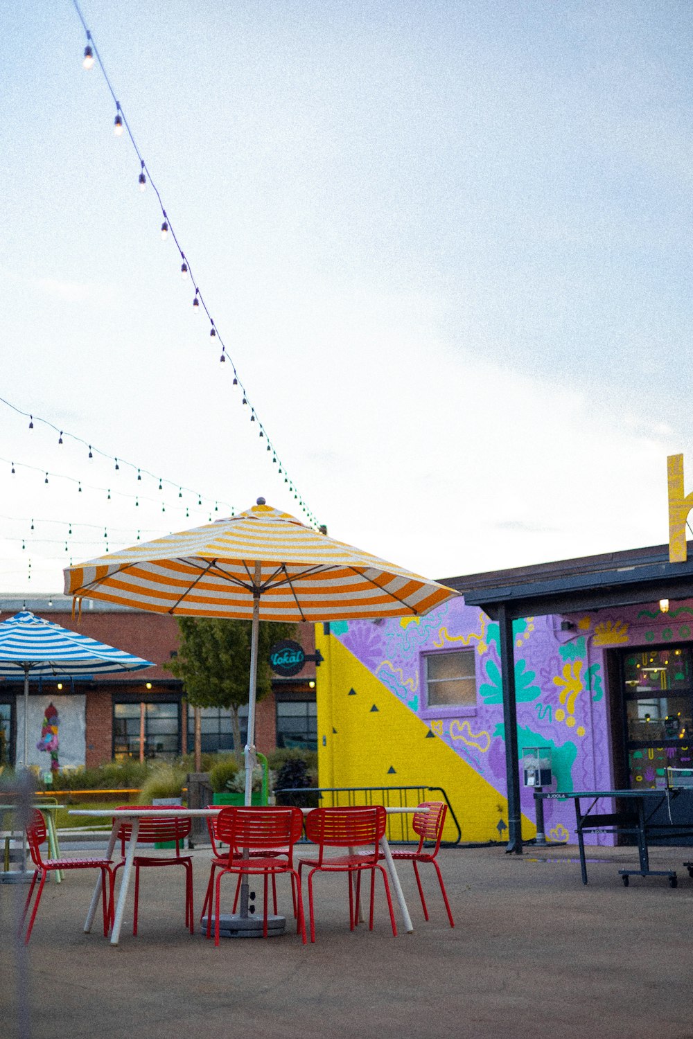 a colorful building with tables and chairs and an umbrella