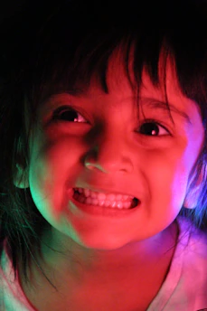 A joyful young person enjoying sour candy with neon pink and yellow lights.