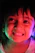 A joyful child holding a glowing neon painting in a dark room filled with colorful neon lights.