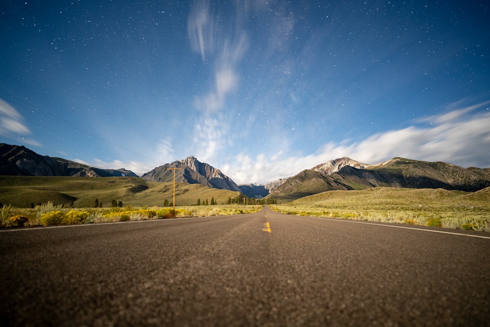 an empty road with mountains in the background