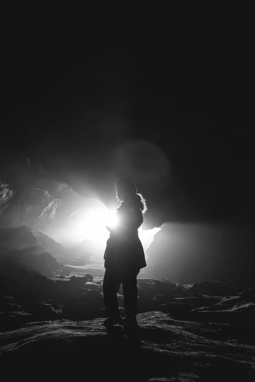 a black and white photo of a person standing in a cave