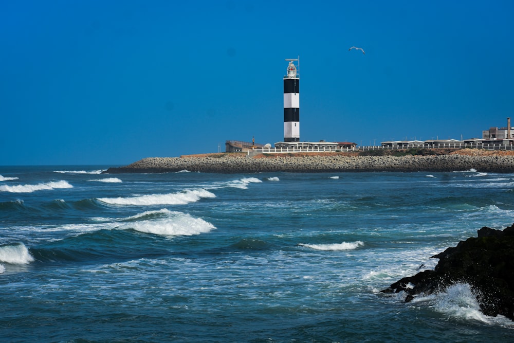 a black and white lighthouse on a rocky shore