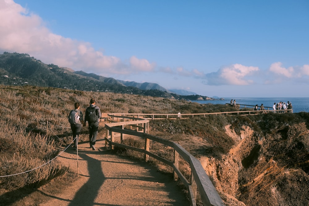 a couple of people walking up a wooden walkway