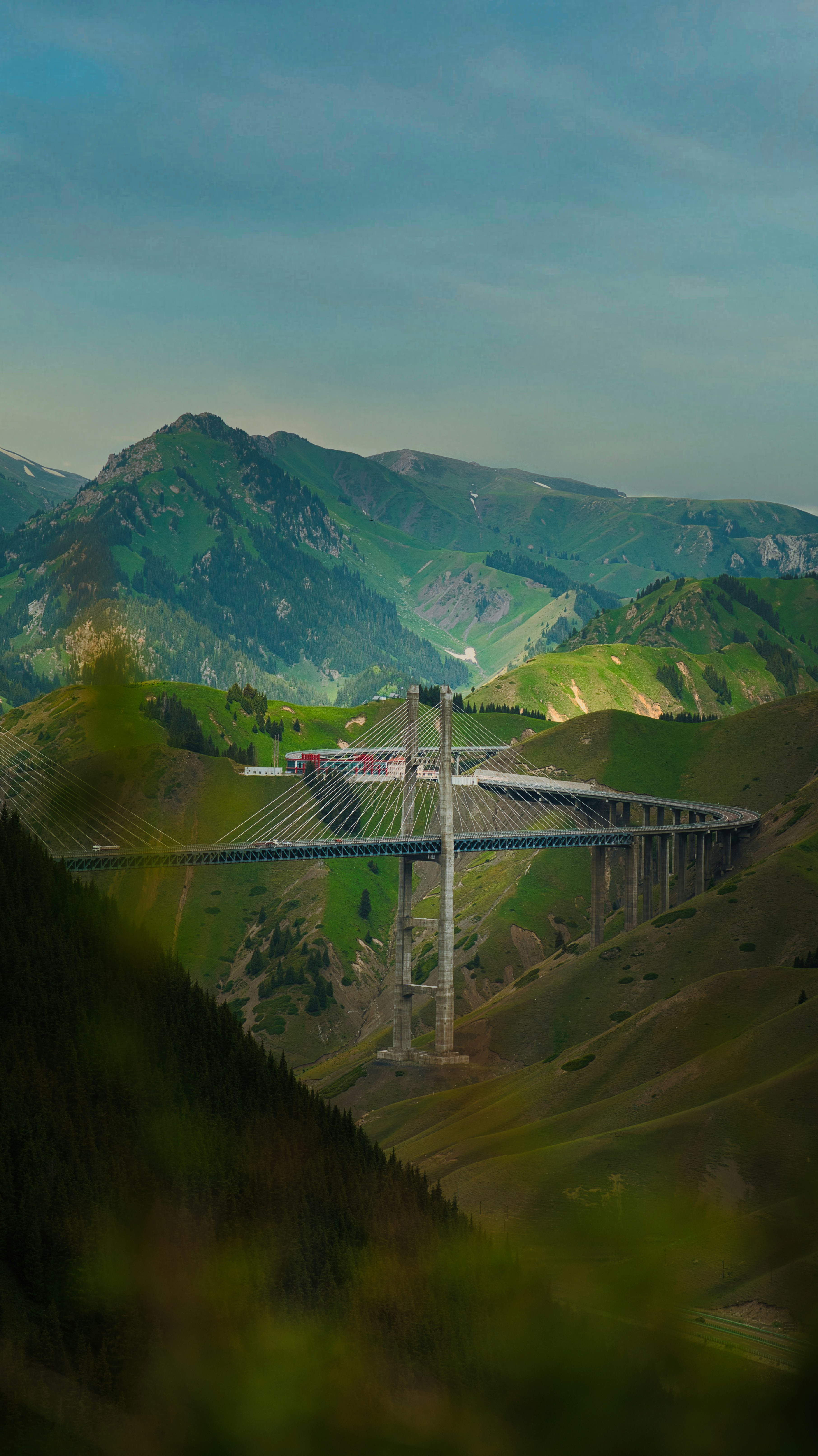 a bridge in the middle of a valley with mountains in the background
