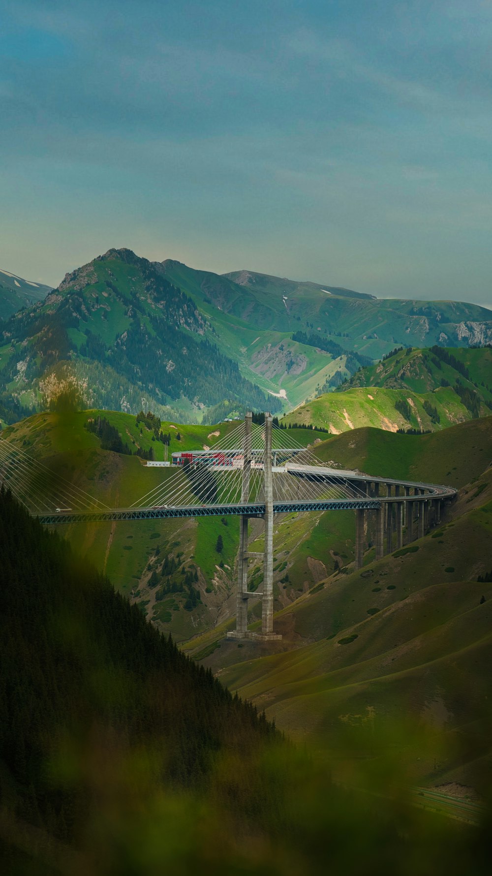 a bridge in the middle of a valley with mountains in the background