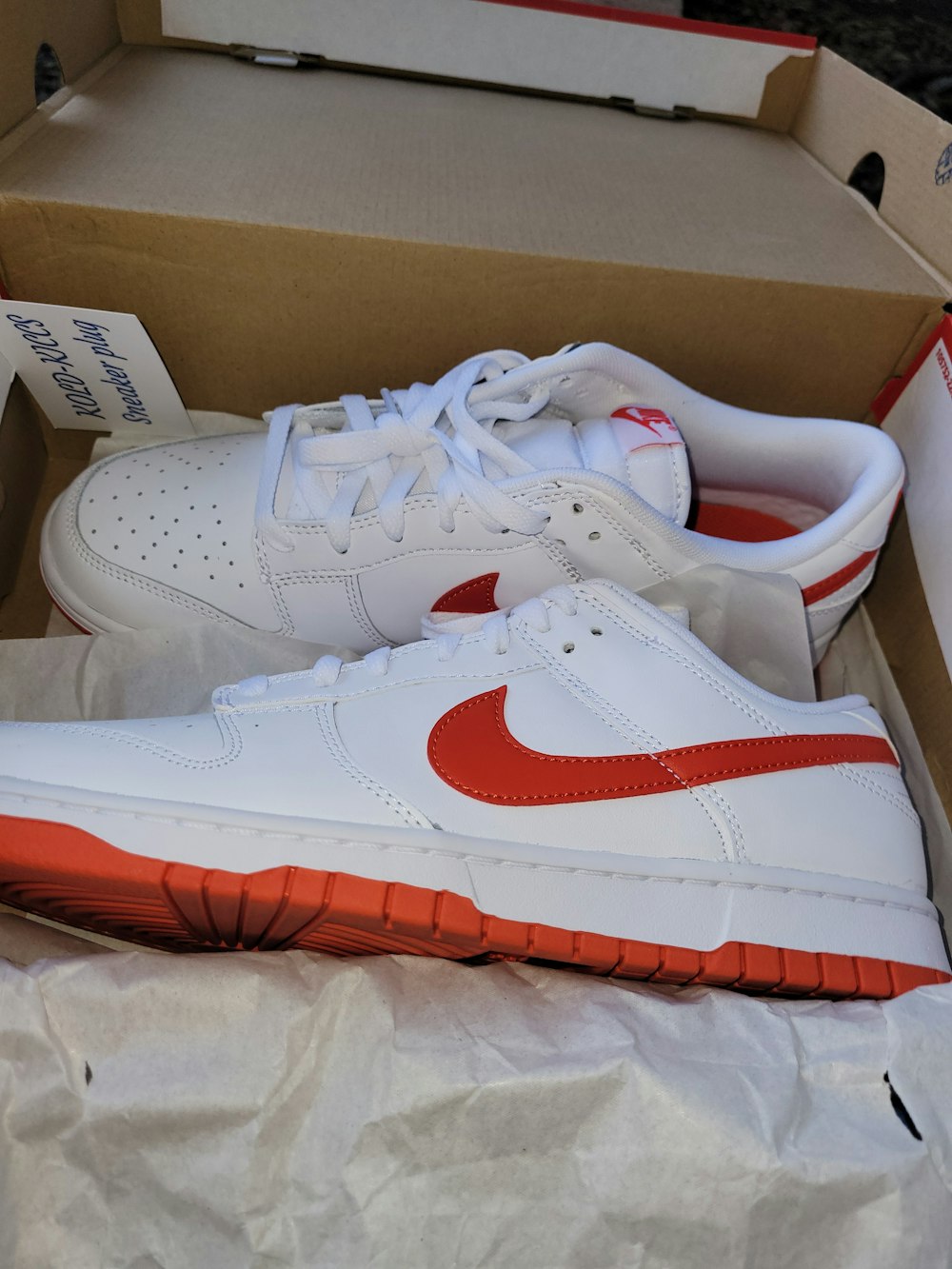 Un par de zapatillas blancas y rojas en una caja