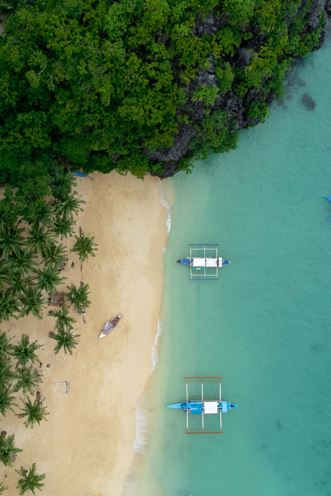 Bird view on the lonely Seven Commandos Beach of El Nido (Palawan, Philippines) with white sand, cristal clear water and green palm trees.