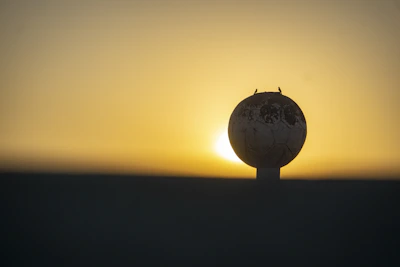 A close-up of a soccer ball soaring towards the goal during a sunset match.