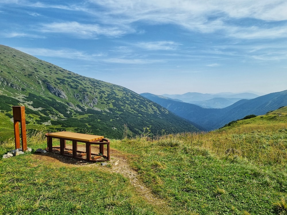 a wooden bench sitting on top of a lush green hillside