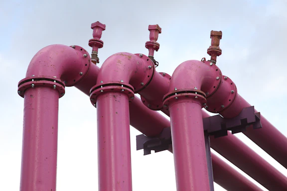 A sleek industrial pipeline with corrosion-resistant valves against a clear blue sky.