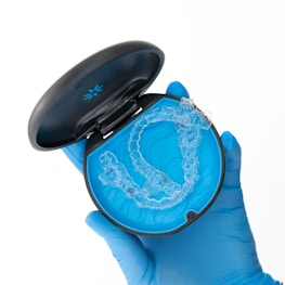 a person in blue gloves holding a plastic object