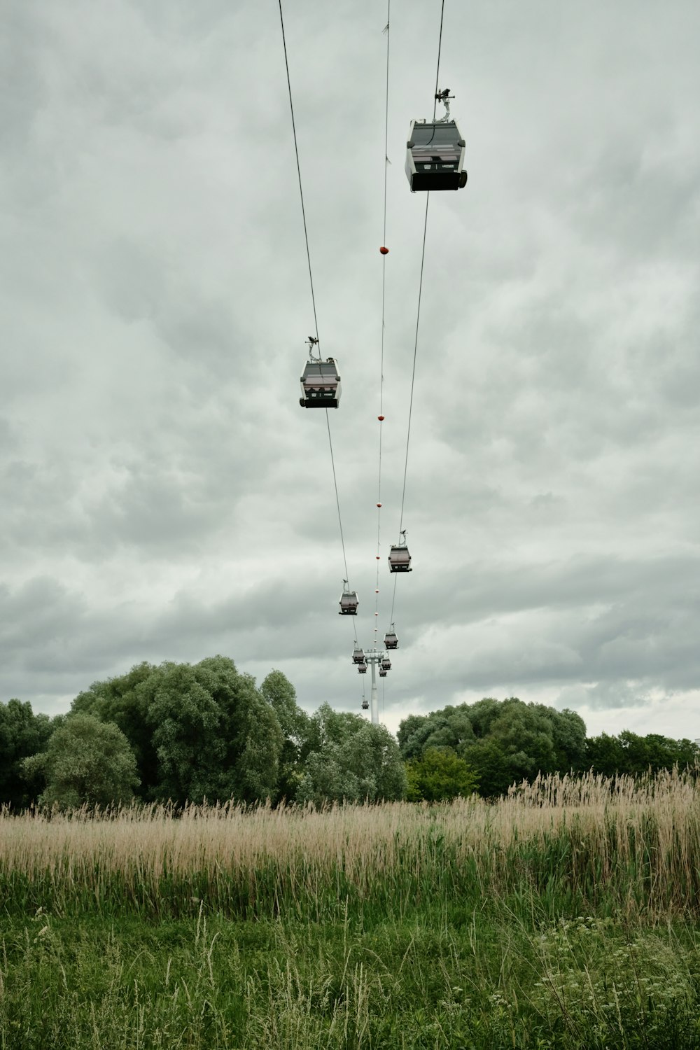 a group of people riding a ski lift over a lush green field